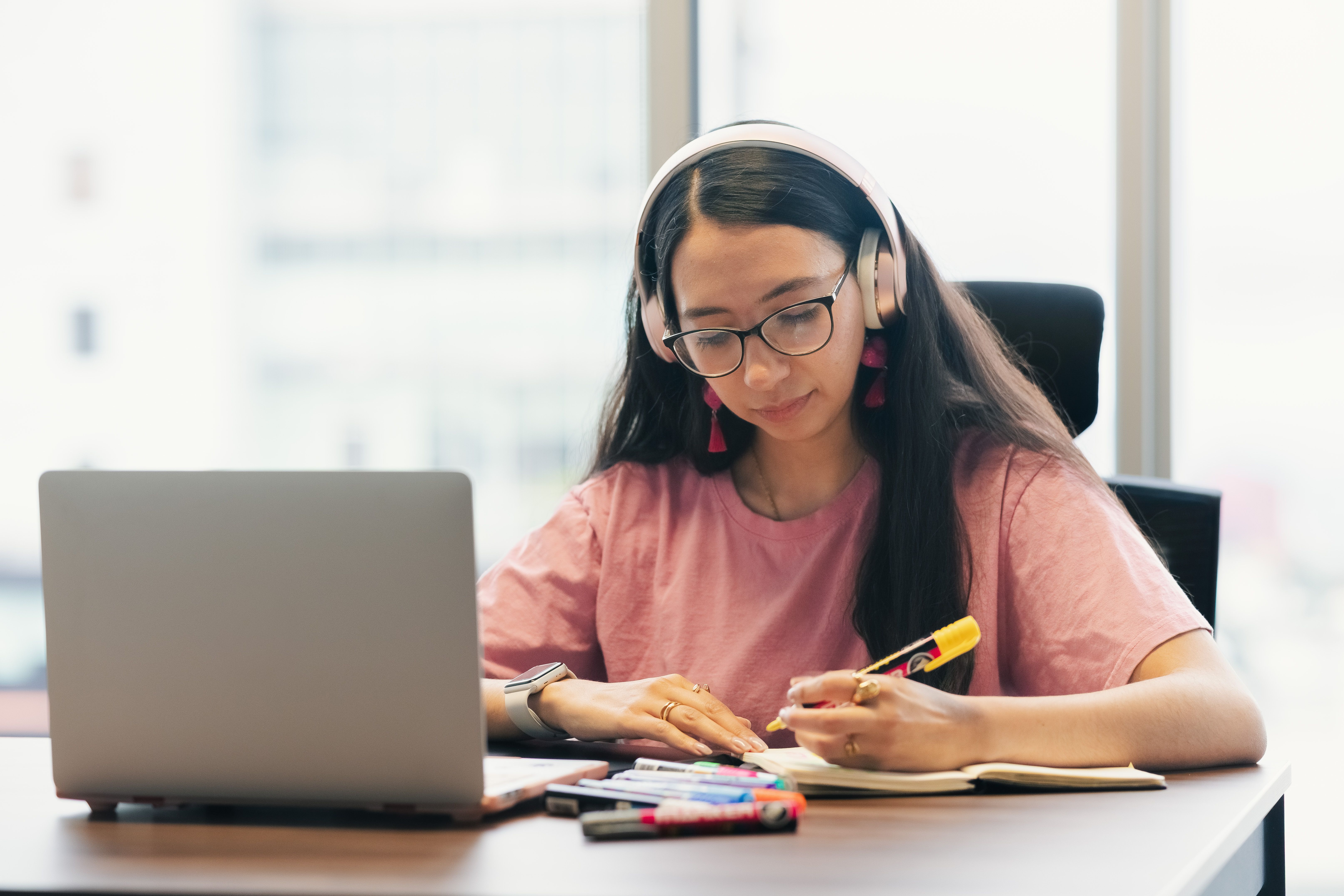 Estudiante trabajando con su portátil y tomando apuntes
