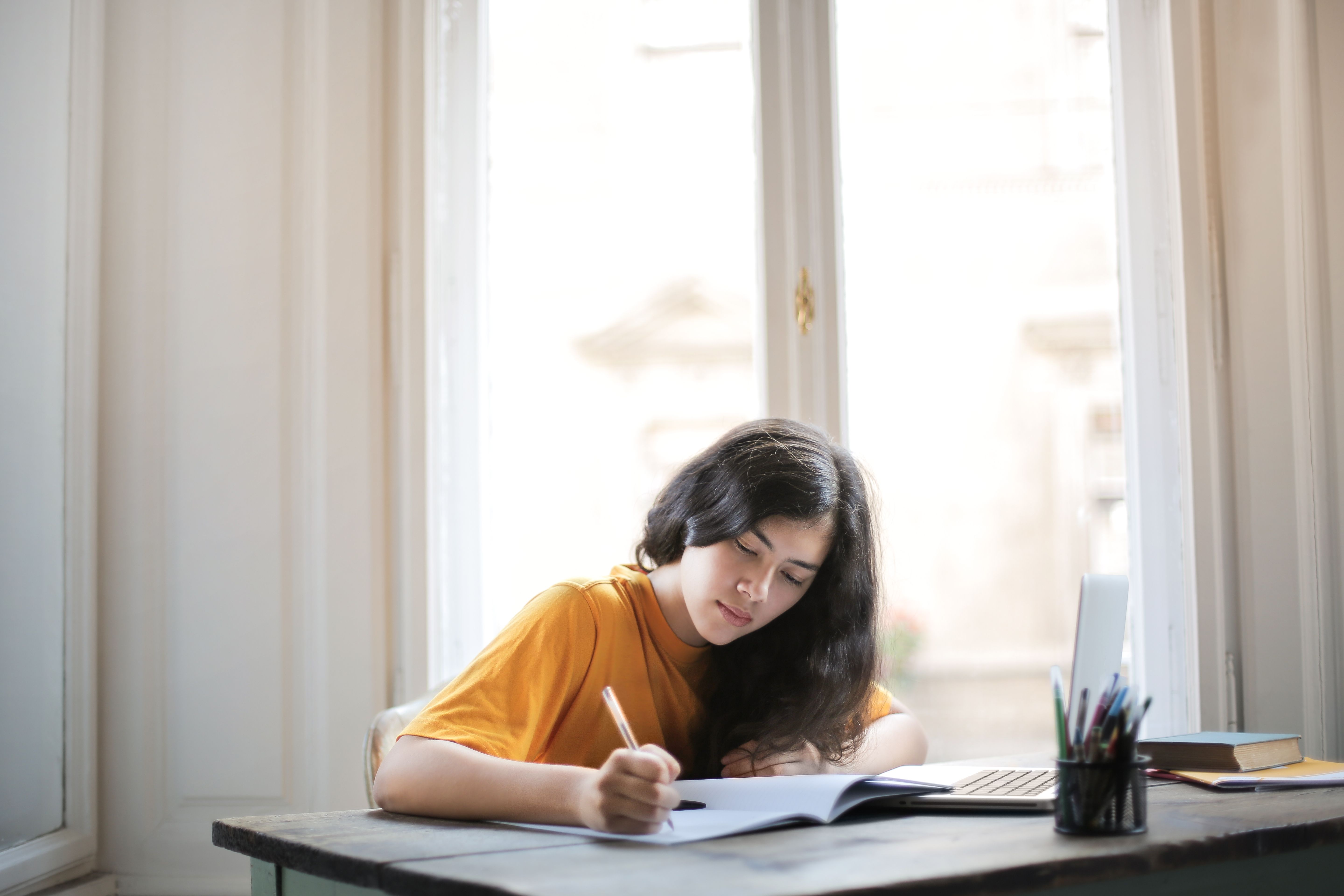 Estudiante preparando sus asignaturas con apuntes y ordenador